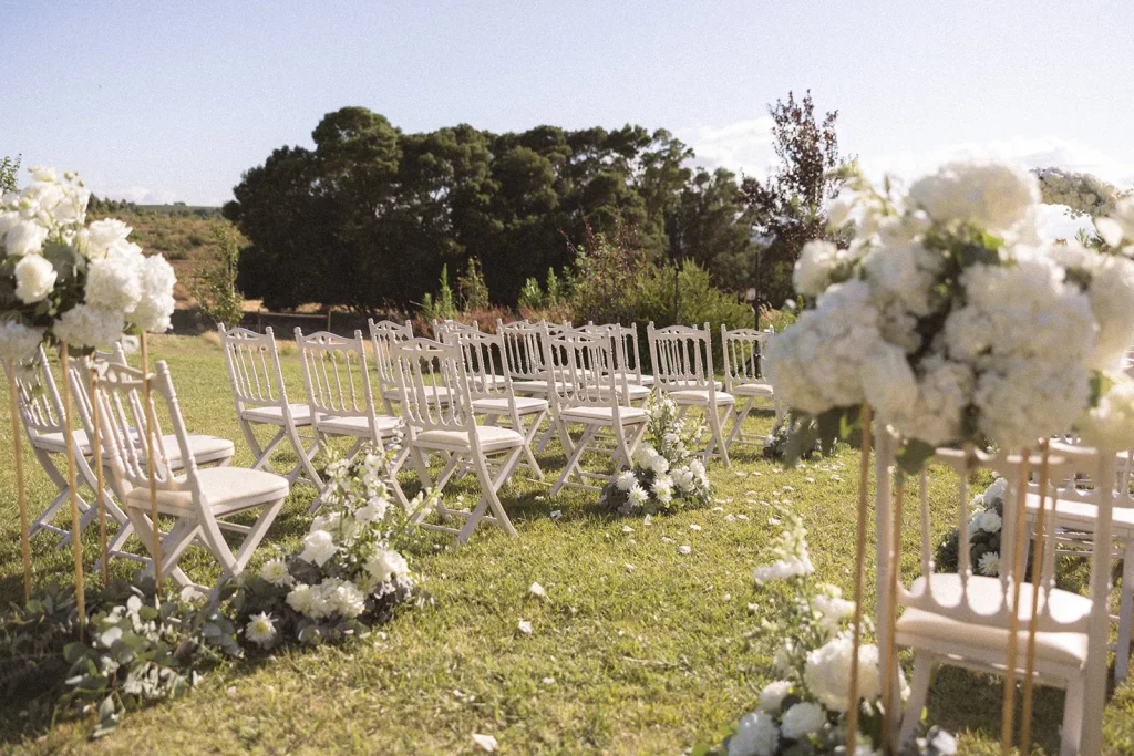 Cerimónia de casamento ao ar livre, com cadeiras brancas e hortênsias num jardim
