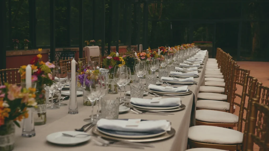 Mesa comprida de banquete com flores silvestres coloridas e cadeiras douradas